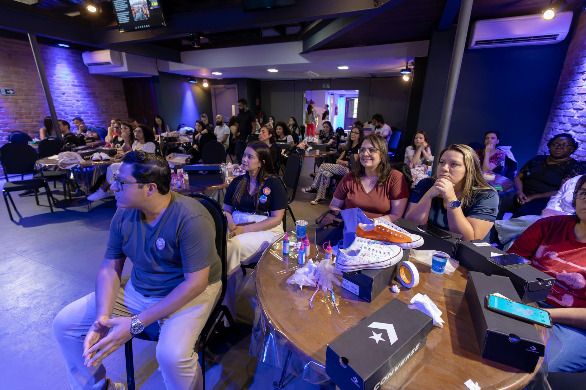 Uczestnicy warsztatów kreatywnych przy stole z butami Converse