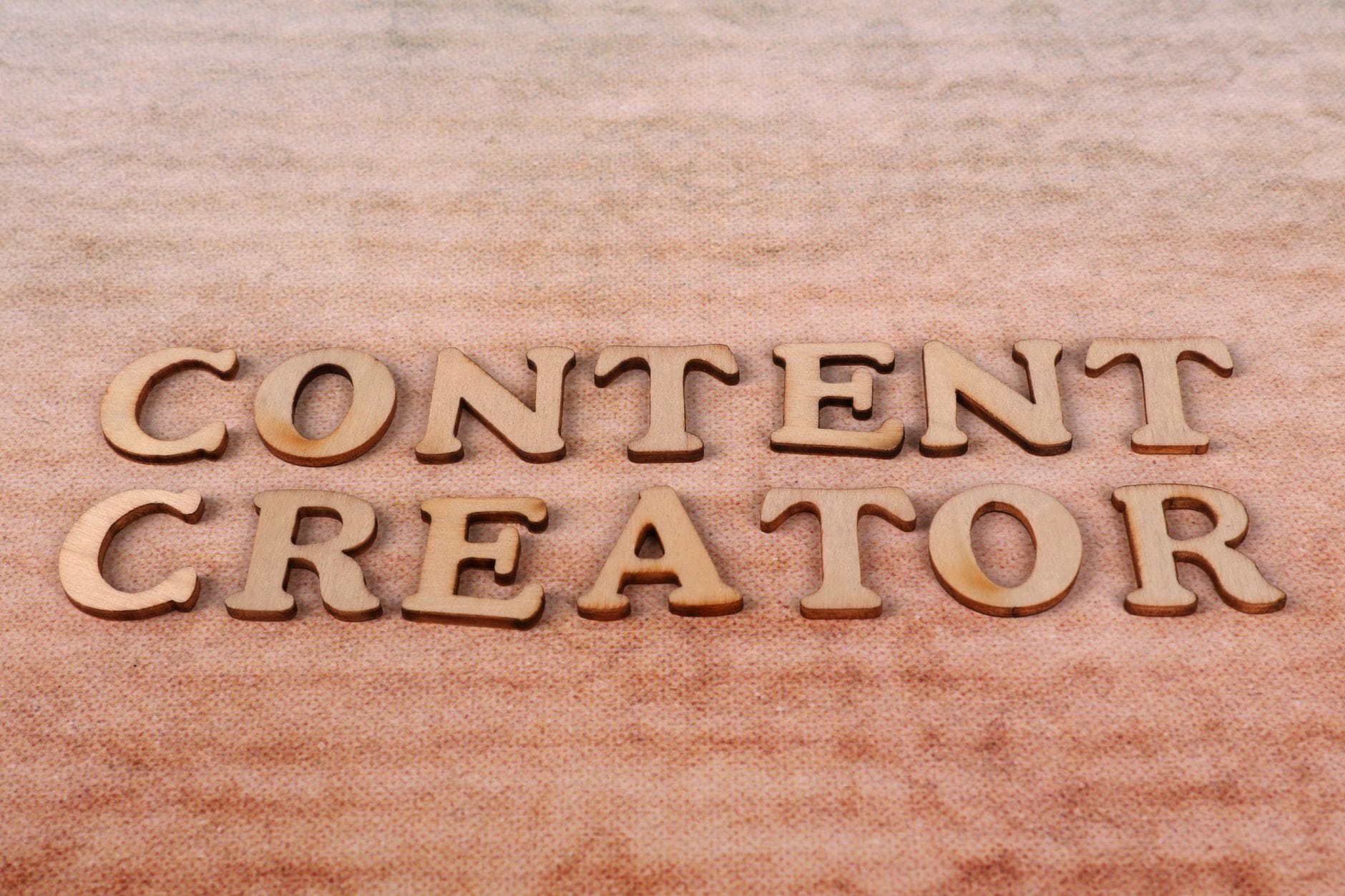 Drewniane litery układające napis Content Creator na tkaninie