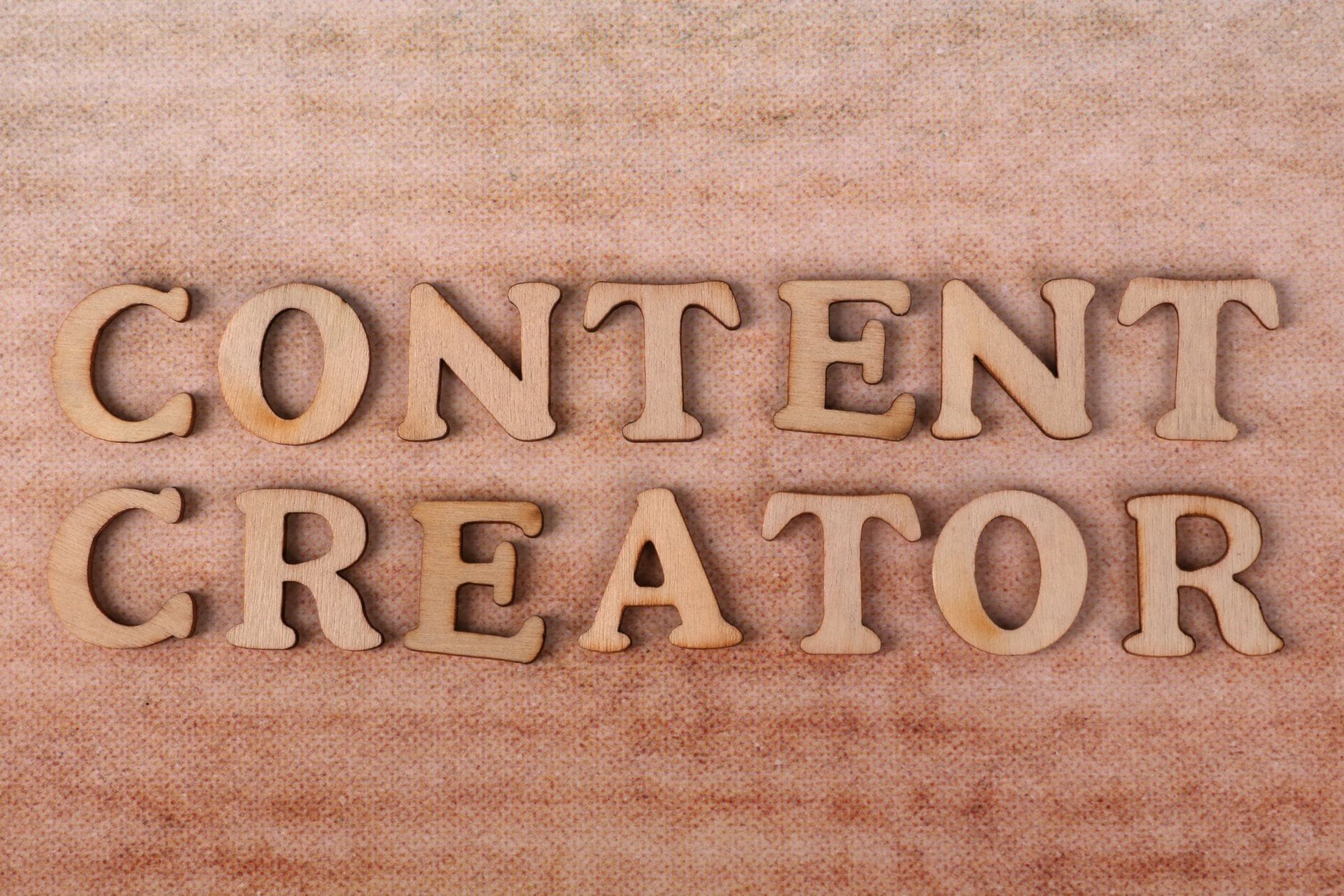 Drewniane litery układające się w napis Content Creator na tkaninie