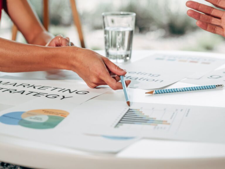 Dłonie omawiające strategię marketingową nad wykresami w biurze